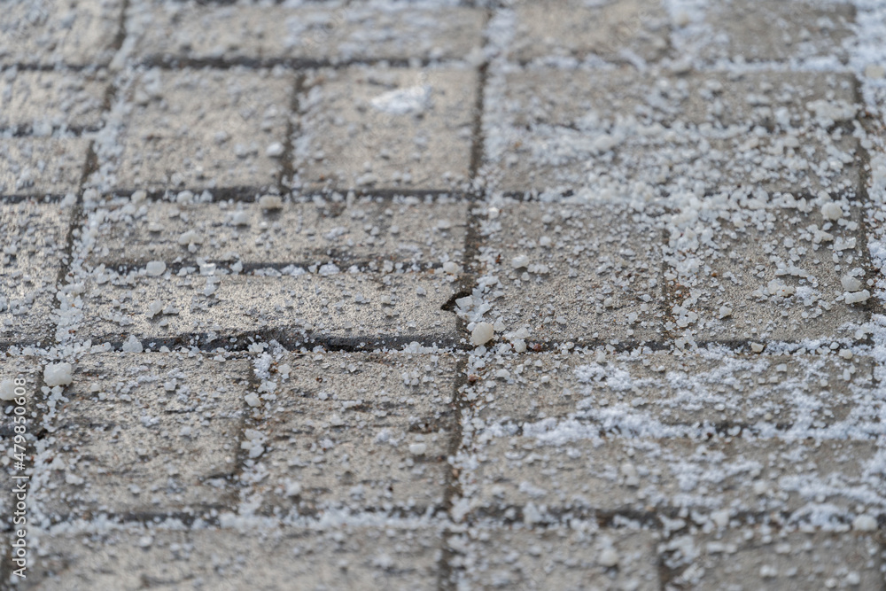De-icing chemicals reagent on asphalt. Pavement is sprinkled with technical salt or salt mixtures based on it. Effective tool to fight ice on roads in winter season. . De-icing chemicals reagent on asphalt. Pavement is sprinkled with technical salt or salt mixtures based on it. Effective tool to fight ice on roads in winter season. .