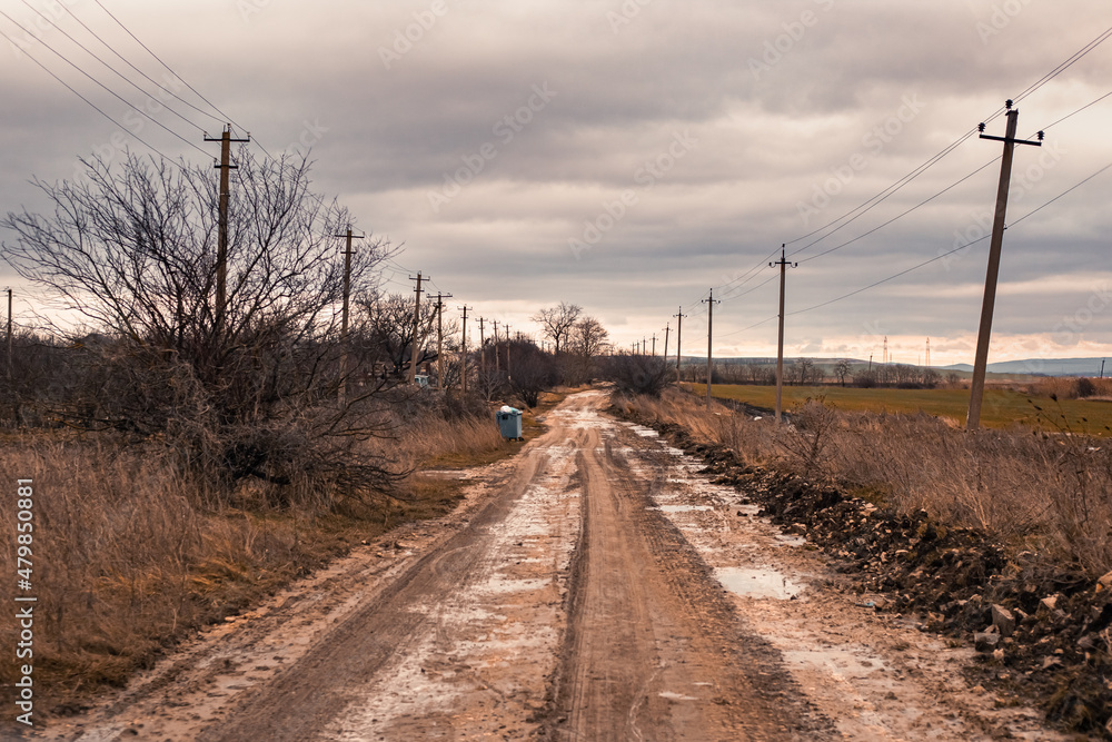 Russian rural dirt road in late autumn on a cloudy day after rains. Dirty track and puddles, poor traffic