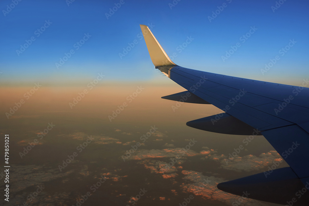 Fototapeta premium View to the wing of airplane in the sky during sunset. Travel and transportation concept