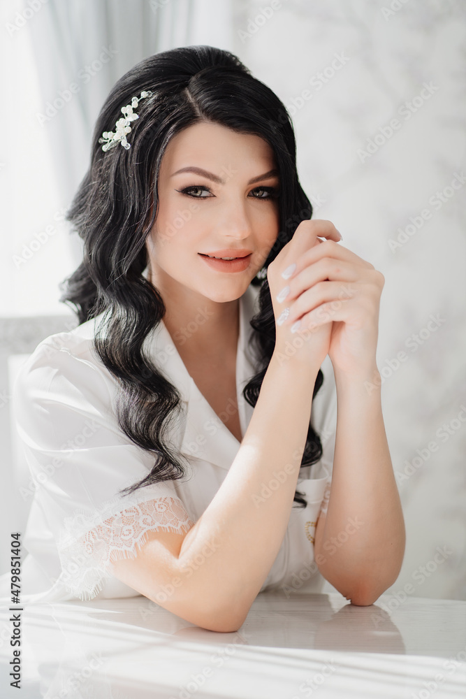 brunette bride in white silk pajamas with styling and makeup at the table brunette bride in white silk pajamas with styling and makeup at the table