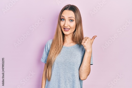 Wallpaper Mural Young blonde girl wearing casual t shirt smiling with happy face looking and pointing to the side with thumb up. Torontodigital.ca