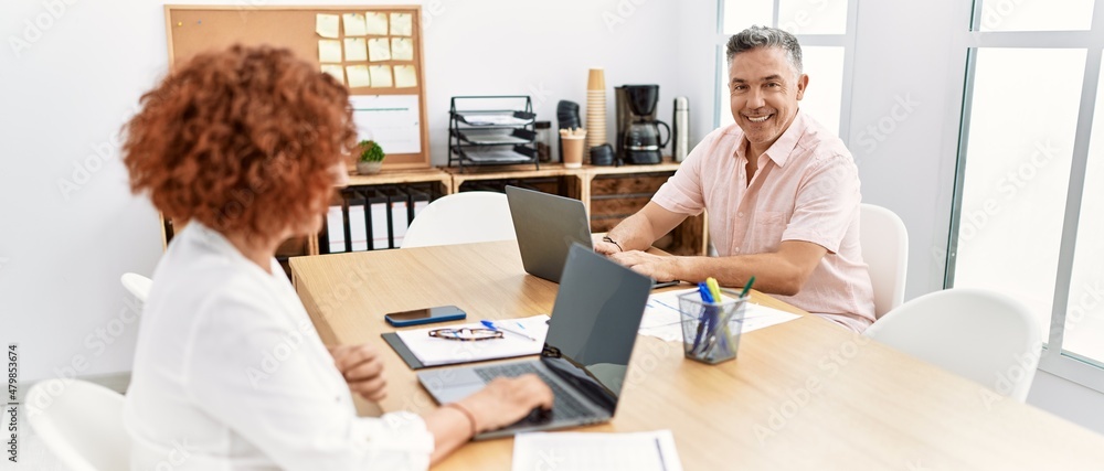 Middle age man and woman business workers using laptop working at office Middle age man and woman business workers using laptop working at office