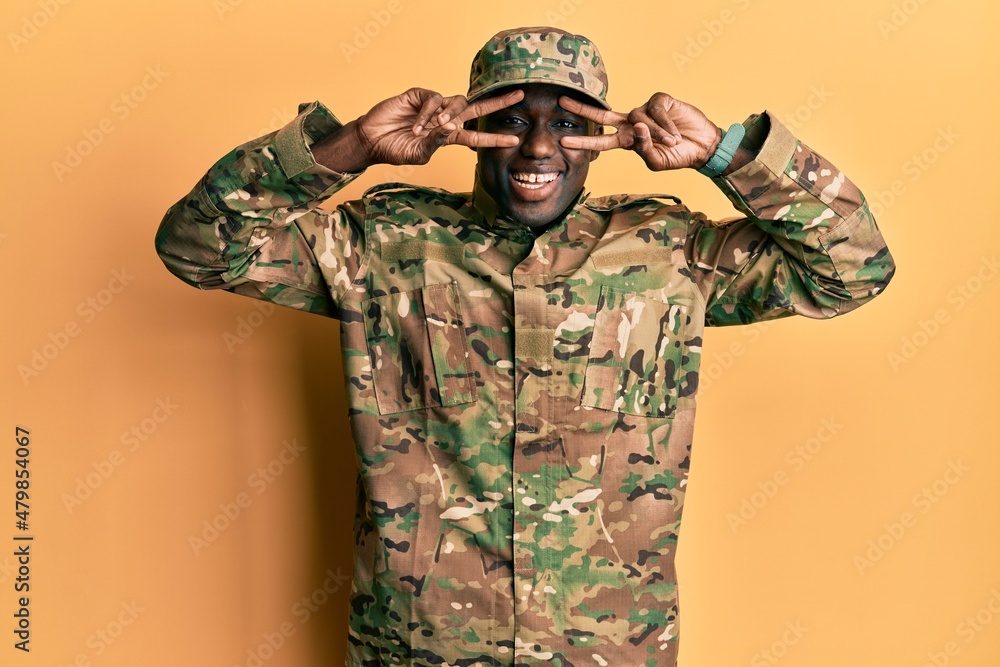 Young african american man wearing army uniform doing peace symbol with fingers over face, smiling cheerful showing victory Young african american man wearing army uniform doing peace symbol with fingers over face, smiling cheerful showing victory