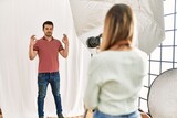 Woman photographer talking pictures of man posing as model at photography studio relax and smiling with eyes closed doing meditation gesture with fingers. yoga concept.
