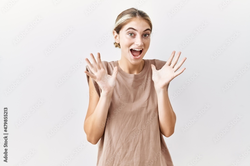 Young blonde woman standing over isolated background celebrating crazy and amazed for success with arms raised and open eyes screaming excited. winner concept Young blonde woman standing over isolated background celebrating crazy and amazed for success with arms raised and open eyes screaming excited. winner concept
