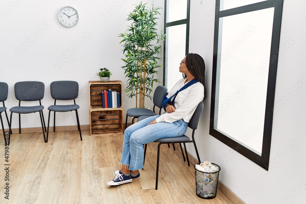 Young african american woman injury on arm sitting on chair at clinic waiting room