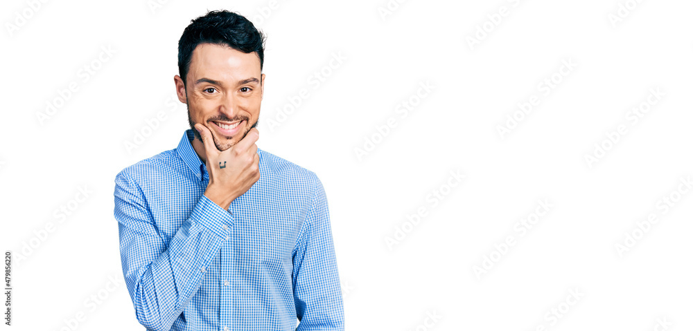 Hispanic man with beard wearing casual business shirt looking confident at the camera smiling with crossed arms and hand raised on chin. thinking positive. Hispanic man with beard wearing casual business shirt looking confident at the camera smiling with crossed arms and hand raised on chin. thinking positive.