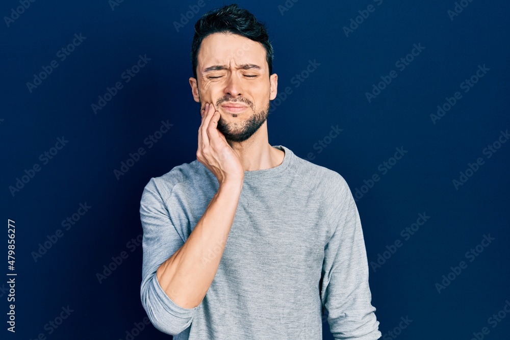 Young hispanic man wearing casual clothes touching mouth with hand with painful expression because of toothache or dental illness on teeth. dentist