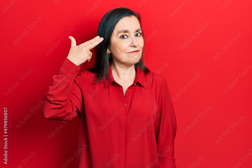 Middle age hispanic woman wearing casual clothes shooting and killing oneself pointing hand and fingers to head like gun, suicide gesture. Middle age hispanic woman wearing casual clothes shooting and killing oneself pointing hand and fingers to head like gun, suicide gesture.