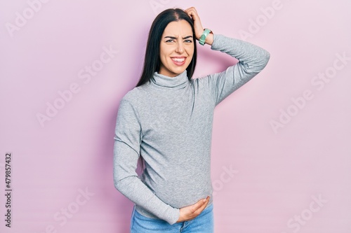 Obraz na plátně Beautiful woman with blue eyes expecting a baby, touching pregnant belly confuse and wondering about question