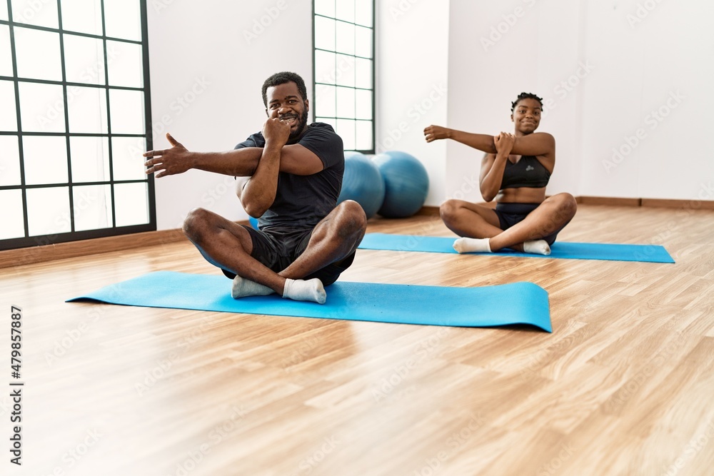 Young african american sporty couple smiling happy training yoga at sport center. Young african american sporty couple smiling happy training yoga at sport center.