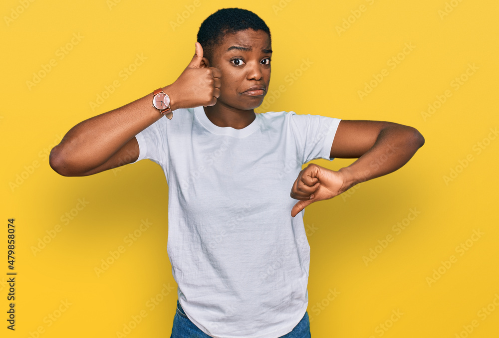 Young african american woman wearing casual white t shirt doing thumbs up and down, disagreement and agreement expression. crazy conflict Young african american woman wearing casual white t shirt doing thumbs up and down, disagreement and agreement expression. crazy conflict