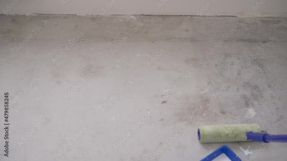 The concept of selfleveling floors. Worker puts primer on concrete