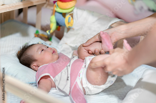 Fotografi Parent help asian baby for burp by cycling massage technique, Burping babyconcep