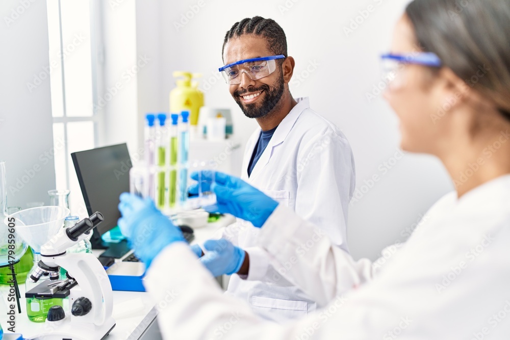 Man and woman scientist partners smiling confident holding test tube at laboratory Man and woman scientist partners smiling confident holding test tube at laboratory