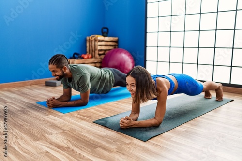 Man and woman couple smiling confident training abs exercise at sport center