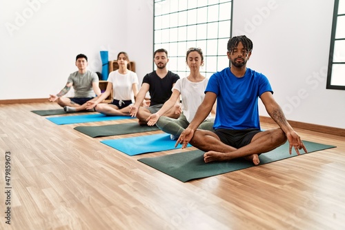 Group of young sporty people concentrate training yoga at sport center.