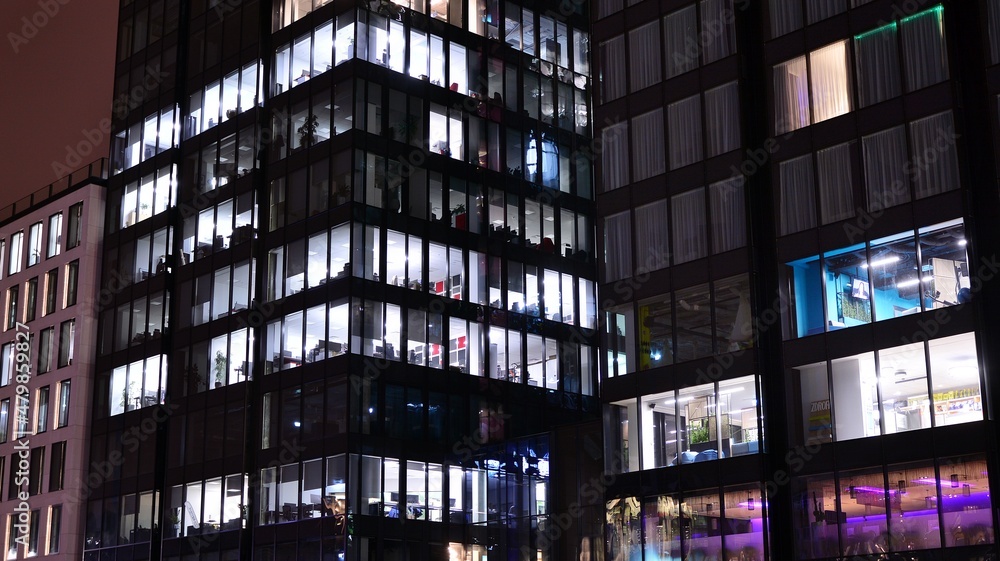 Obraz premium Office building at night, building facade with glass and lights. View with illuminated modern skyscraper.