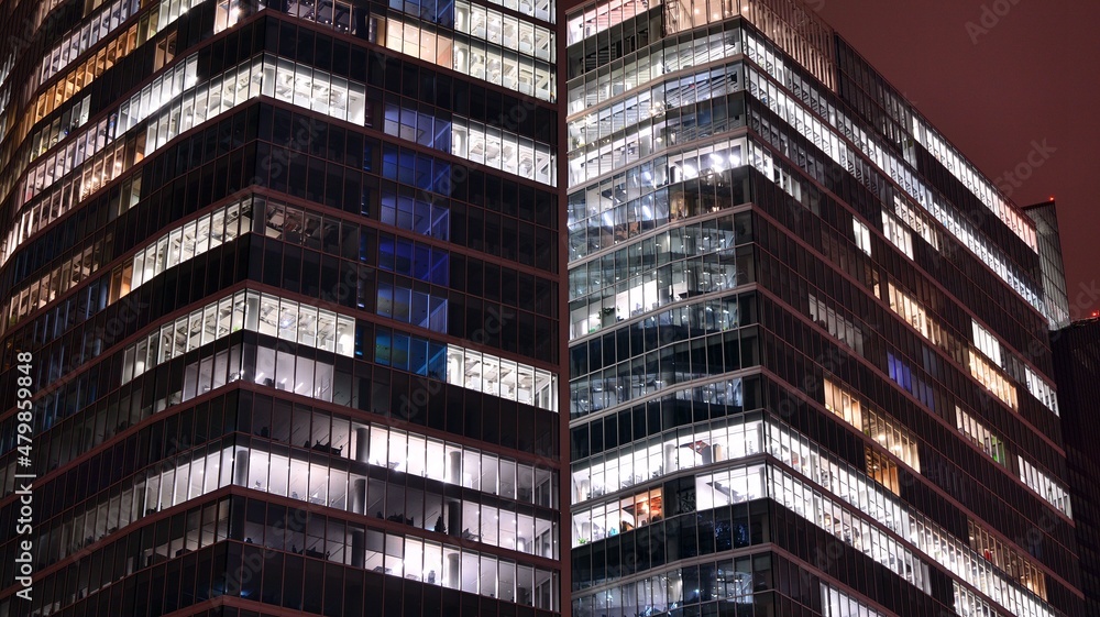Obraz premium Office building at night, building facade with glass and lights. View with illuminated modern skyscraper.