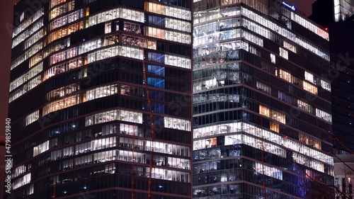 Office building at night, building facade with glass and lights. View with illuminated modern skyscraper.