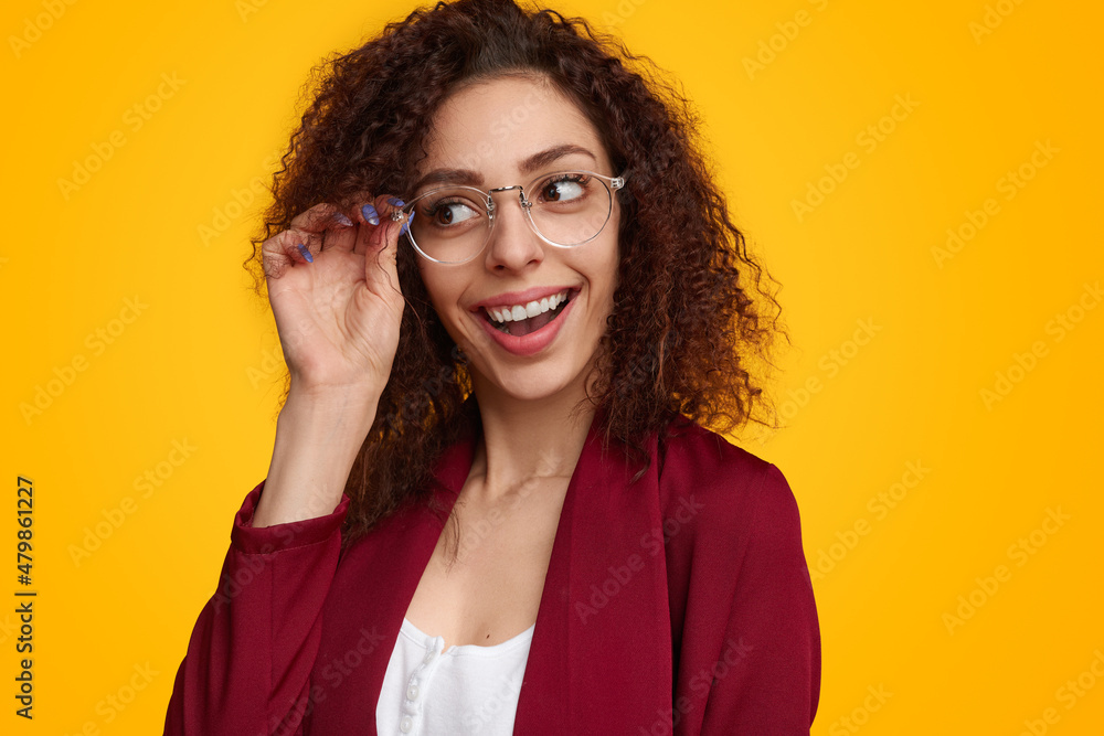 Excited young lady adjusting eyeglasses and looking away in studio Excited young lady adjusting eyeglasses and looking away in studio