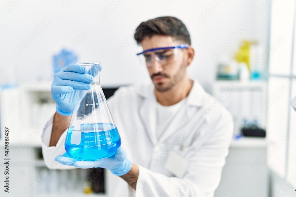 Handsome hispanic man working as scientific holding erlenmeyer flask at laboratory Handsome hispanic man working as scientific holding erlenmeyer flask at laboratory