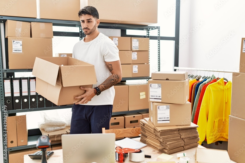 Young hispanic man working at small business ecommerce skeptic and nervous, frowning upset because of problem. negative person. Young hispanic man working at small business ecommerce skeptic and nervous, frowning upset because of problem. negative person.
