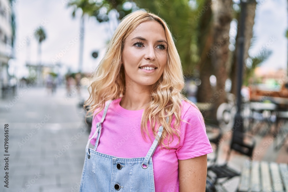 Young blonde woman smiling confident at street