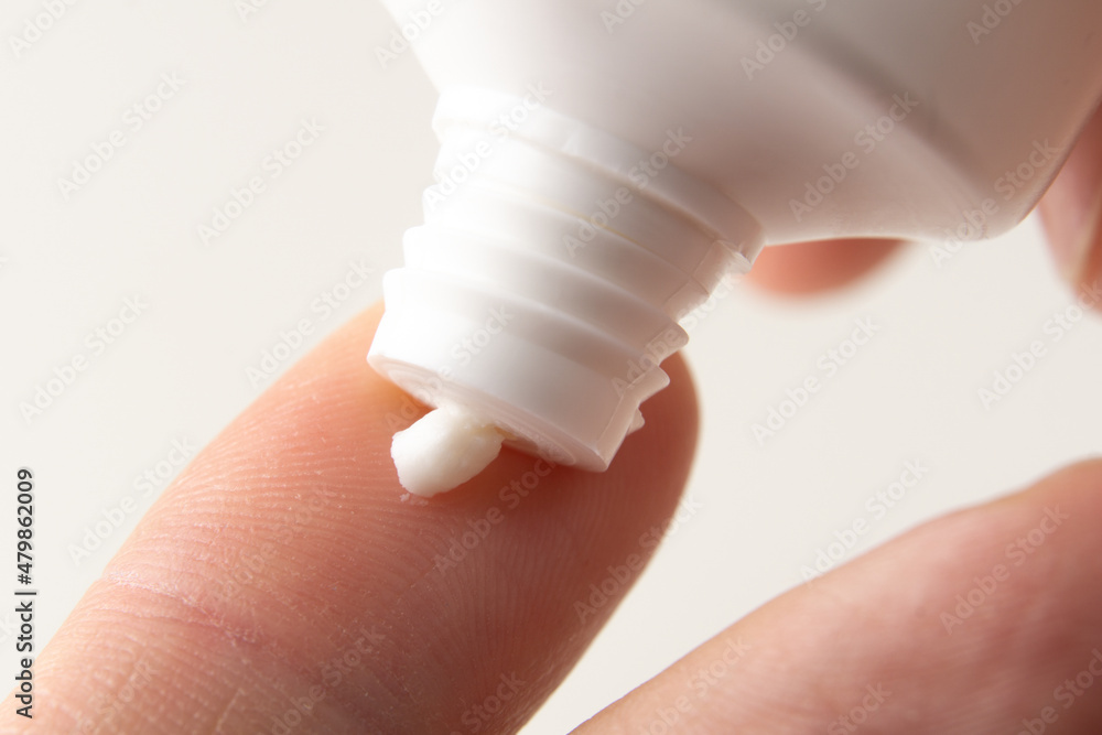 Cream is squeezed onto a man's finger from a white tube. Using hand cream. Cream is squeezed onto a man's finger from a white tube. Using hand cream.