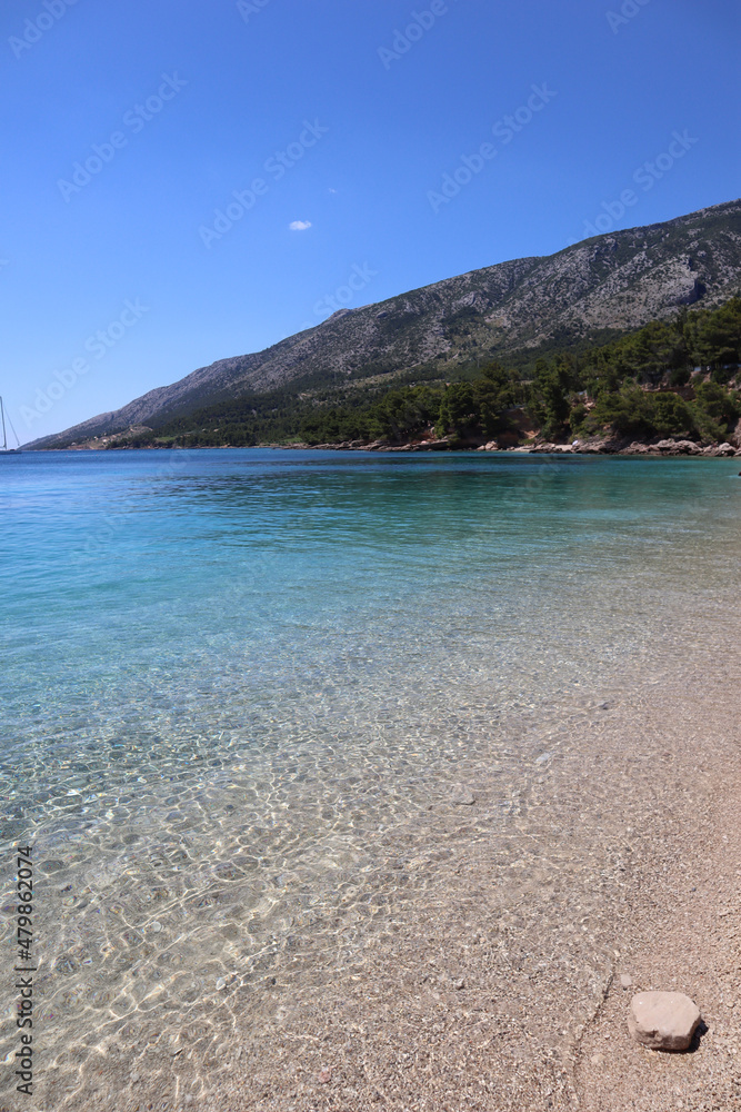 The picturesque Zlatni Rat beach surrounded by mountains overgrown with green pine trees, the island of Brac, Dalmatia, Croatia
