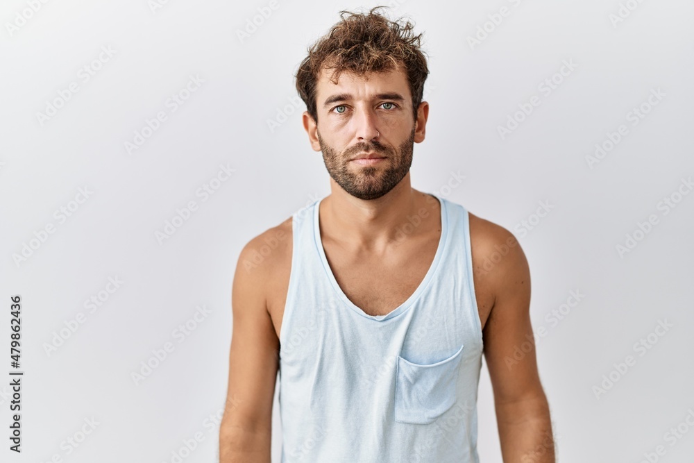 Young handsome man standing over isolated background relaxed with serious expression on face. simple and natural looking at the camera. Young handsome man standing over isolated background relaxed with serious expression on face. simple and natural looking at the camera.