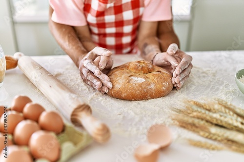 Young couple smiling happy cooking homemade bread at kitchen.