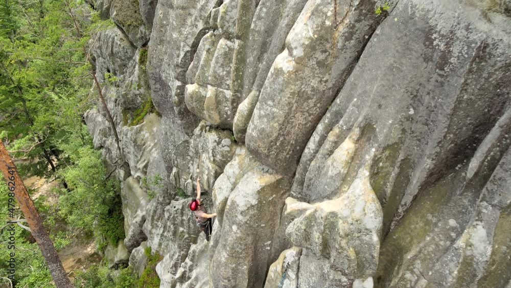 Strong male climber climbing steep wall of rocky mountain. Sportsman overcoming difficult route. Engaging in extreme sports hobby concept Strong male climber climbing steep wall of rocky mountain. Sportsman overcoming difficult route. Engaging in extreme sports hobby concept