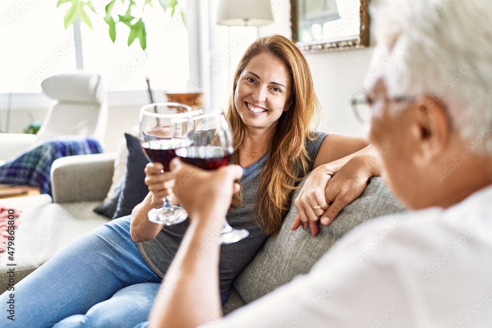 Middle age hispanic couple smiling happy drinking wine sitting on the sofa at home. Middle age hispanic couple smiling happy drinking wine sitting on the sofa at home.