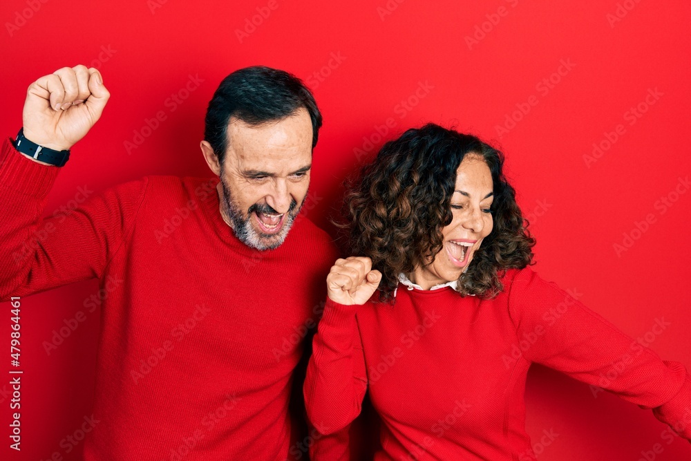 Middle age couple of hispanic woman and man hugging and standing together dancing happy and cheerful, smiling moving casual and confident listening to music Middle age couple of hispanic woman and man hugging and standing together dancing happy and cheerful, smiling moving casual and confident listening to music