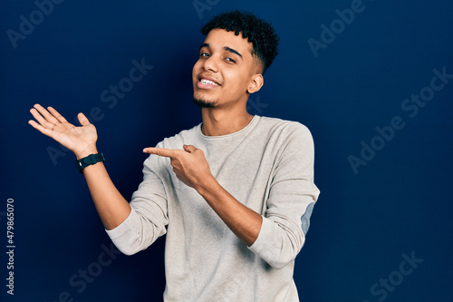 Young african american man wearing casual clothes amazed and smiling to the camera while presenting with hand and pointing with finger.