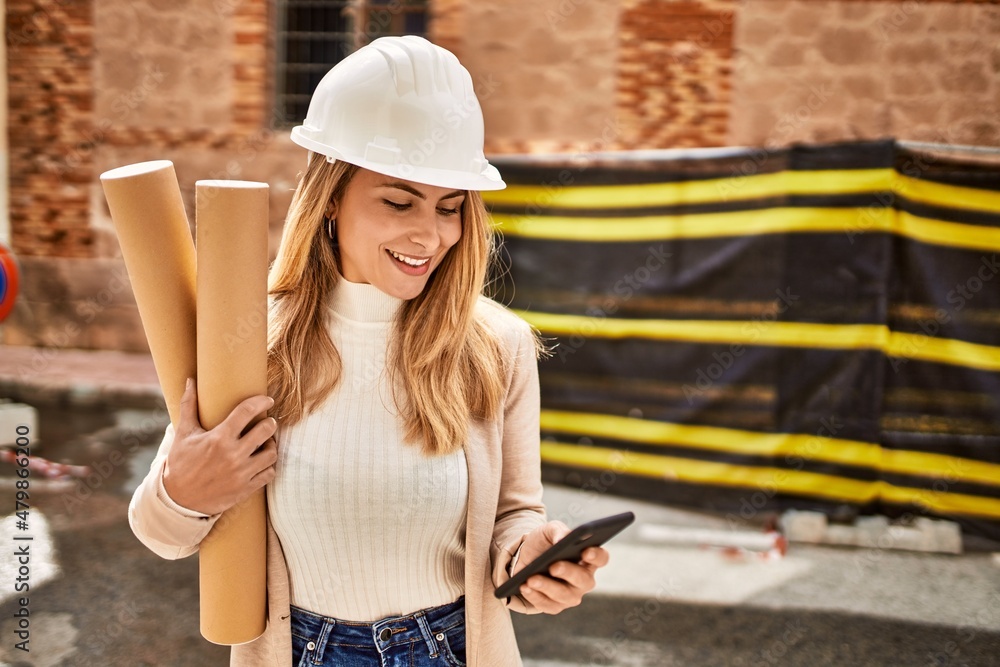 Young blonde woman holding blueprints using smartphone at street Young blonde woman holding blueprints using smartphone at street