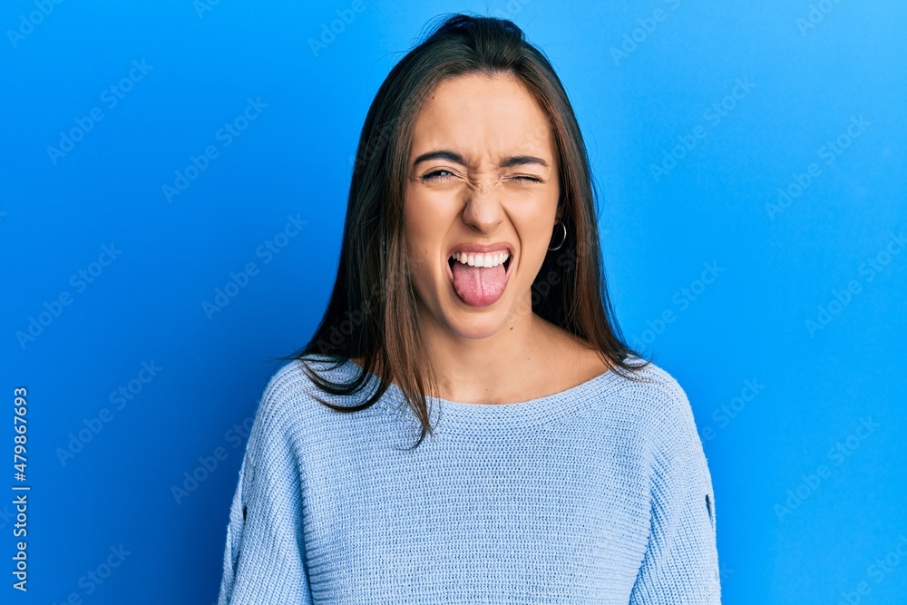 Young hispanic girl wearing casual clothes sticking tongue out happy with funny expression. emotion concept. Young hispanic girl wearing casual clothes sticking tongue out happy with funny expression. emotion concept.
