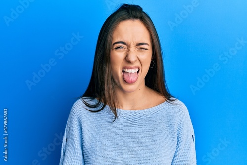 Young hispanic girl wearing casual clothes sticking tongue out happy with funny expression. emotion concept.