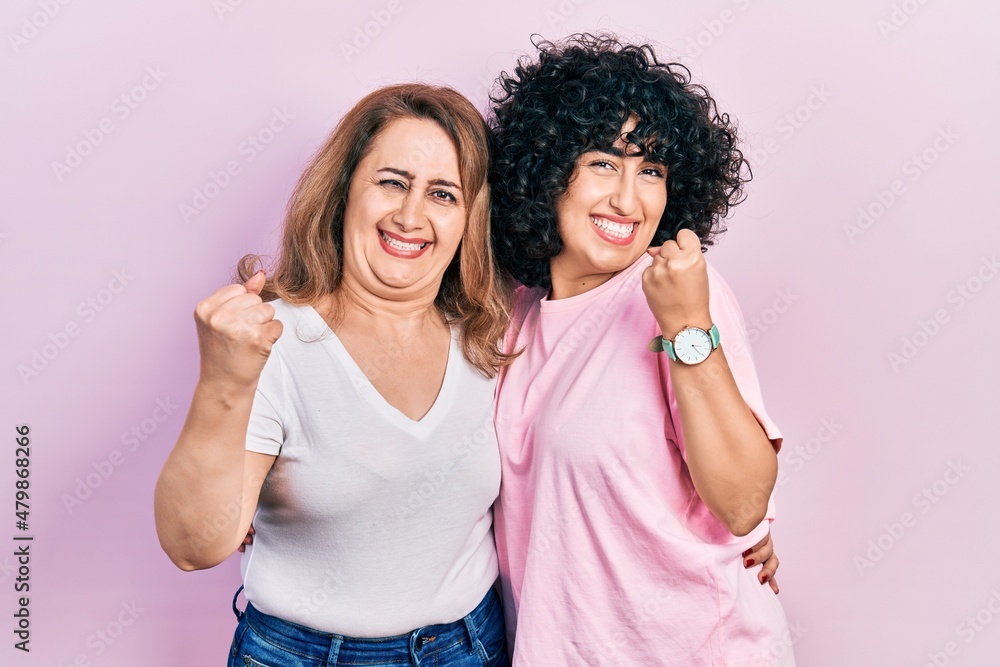Middle east mother and daughter wearing casual clothes very happy and excited doing winner gesture with arms raised, smiling and screaming for success. celebration concept. Middle east mother and daughter wearing casual clothes very happy and excited doing winner gesture with arms raised, smiling and screaming for success. celebration concept.