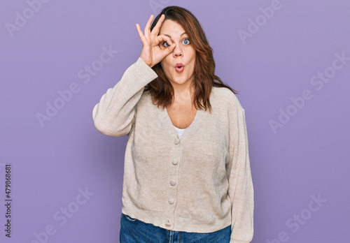 Young plus size woman wearing casual clothes doing ok gesture shocked with surprised face, eye looking through fingers. unbelieving expression. © Krakenimages.com