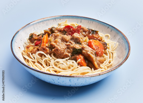  Plate of delicious spaghettis with meat and vegetables over blue background