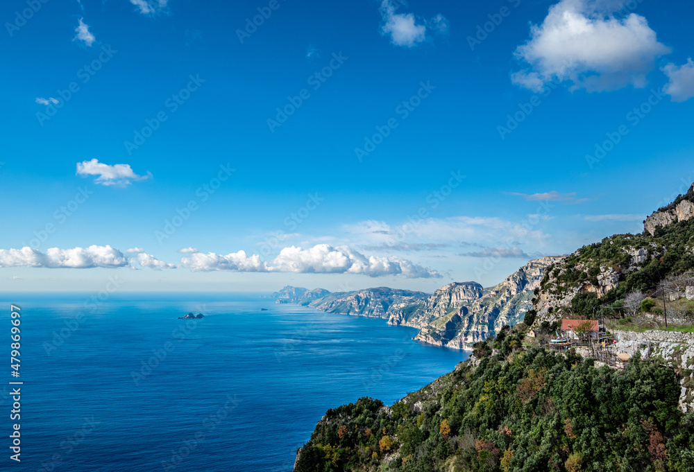 View of the Sorrentine Peninsula and Capri along the Amalfi Coast of Italy, with Tyrhennian Sea under blue skies and clouds