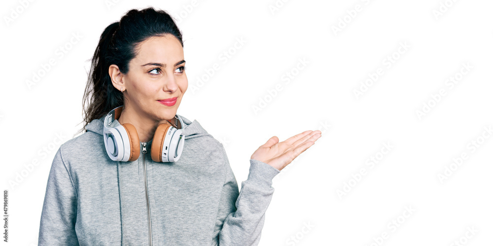 Young hispanic woman wearing gym clothes, using headphones and smart watch smiling looking to the side and staring away thinking. Young hispanic woman wearing gym clothes, using headphones and smart watch smiling looking to the side and staring away thinking.