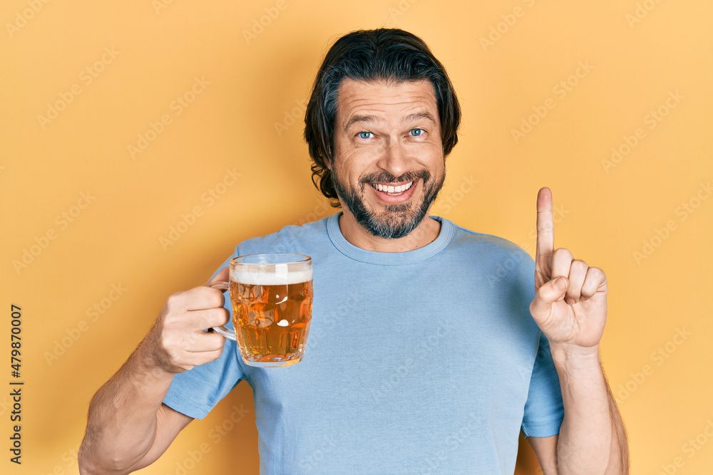 Middle age caucasian man drinking a jar of beer smiling with an idea or question pointing finger with happy face, number one Middle age caucasian man drinking a jar of beer smiling with an idea or question pointing finger with happy face, number one