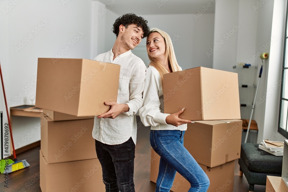 Young beautiful couple smiling happy holding cardboard box at new home. Young beautiful couple smiling happy holding cardboard box at new home.