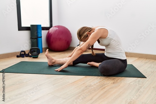 Young caucasian woman stretching at sport center