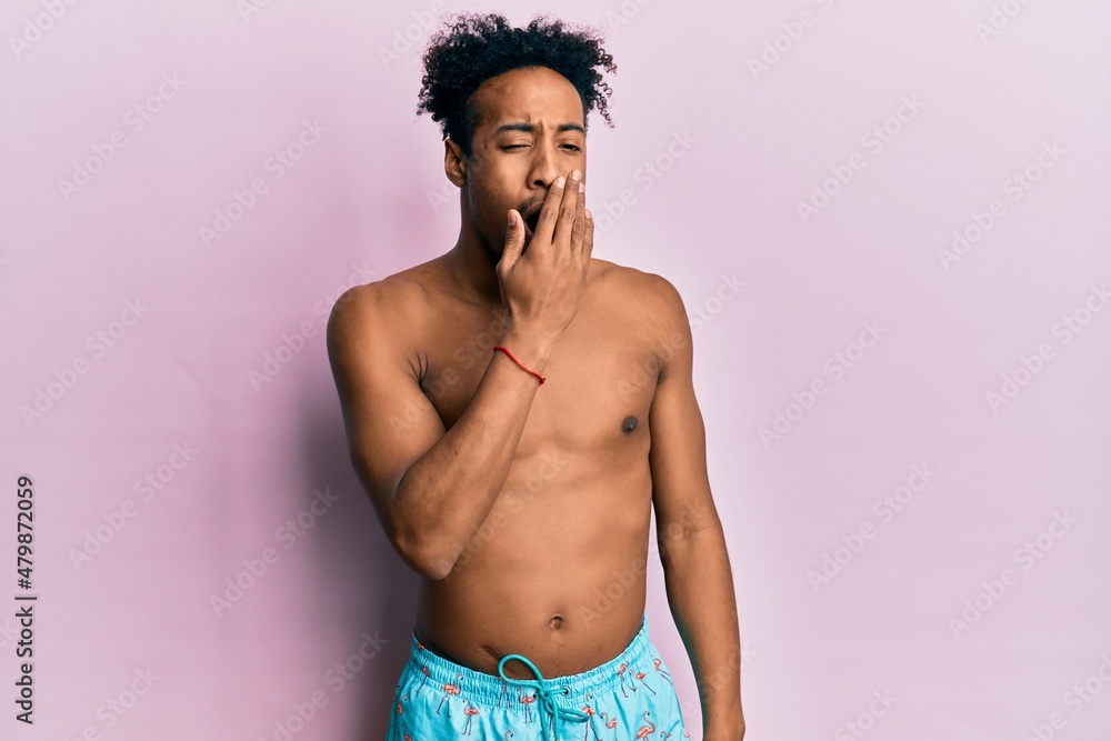 Fototapeta premium Young african american man with beard wearing swimsuit bored yawning tired covering mouth with hand. restless and sleepiness.