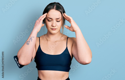 Young hispanic woman wearing sportswear with hand on head for pain in head because stress. suffering migraine.