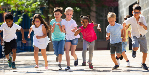 Group of happy kids running in race in the street and laughing outdoors